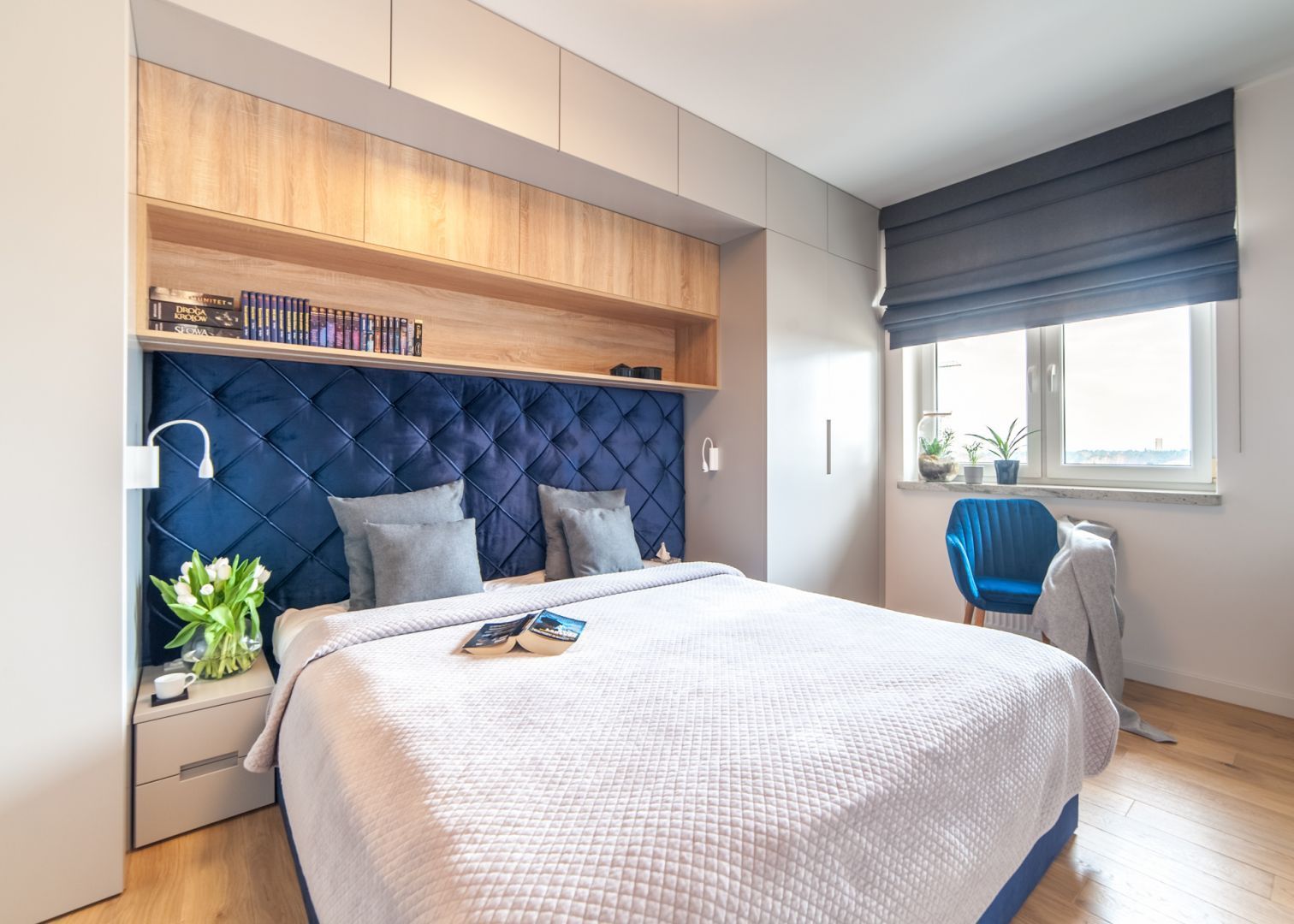 Ściana za łóżkiem w sypialni wykończona jest tapicerowany zagłówkiem w niebieskim kolorze. Projekt: Ewelina Para, RED design. Fot. Adam Woropiński www.bardzo.photo.pl