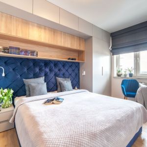 Ściana za łóżkiem w sypialni wykończona jest tapicerowany zagłówkiem w niebieskim kolorze. Projekt: Ewelina Para, RED design. Fot. Adam Woropiński www.bardzo.photo.pl