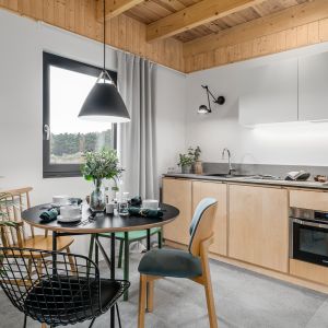 Zabudowa kuchenna w drewnianych wybarwieniach nie musi kojarzyć się z siermiężnymi meblami minionej epoki. Projekt Raca Architekci. Fot. Fotomohito