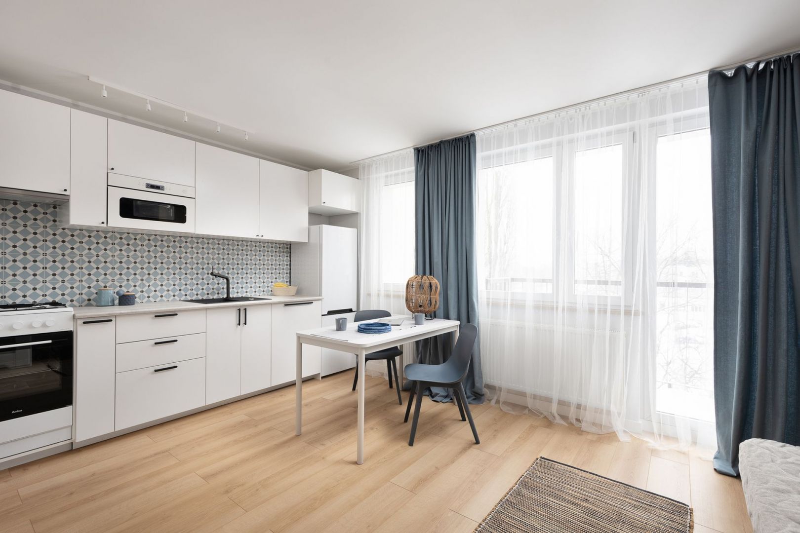 Biała kuchnia, jadalnia, salon i sypialnia to jedna otwarta przestrzeń. Projekt wnętrza, stylizacja: Ola Dąbrówka, pracownia Good Vibes Interiors. Zdjęcia: Mikołaj Dąbrowski