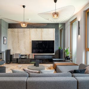 Ściana za telewizorem w salonie wykończona jest nieobrobionym trawertynem z otworami. Kamień jest podświetlany od tyłu, aby uwypuklić jego naturalną strukturę. Projekt: Dorota Kwiecień, Gabriela Gajek Zakolska. Fot. Karol Kleszyk