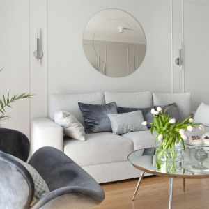 Nad sofą zawisło okrągłe lustro, które nawiązuje do stolika kawowego z okrągłym lustrzanym blatem. Projekt: Studio Projektowania Miśkiewicz Design. Fot. Anna Powałowska