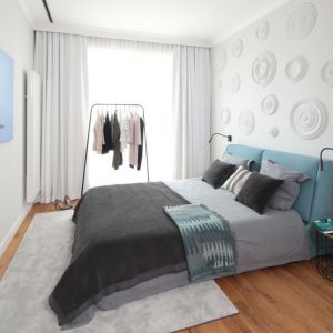 Ściana za łóżkiem w sypialni wykończona jest sztukaterią, a sama sypialnia utrzymana w chłodnej kolorystyce. Projekt Katarzyna Mikulska-Sękalska. Fot. Bartosz Jarosz