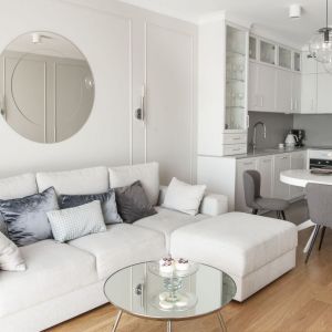 Ściana za kanapa w salonie wykończona jest listwami sztukateryjnymi, dzięki czemu przypominają słynną angielską boazerię. Projekt: Studio Projektowania Miśkiewicz Design. Fot. Anna Powałowska
