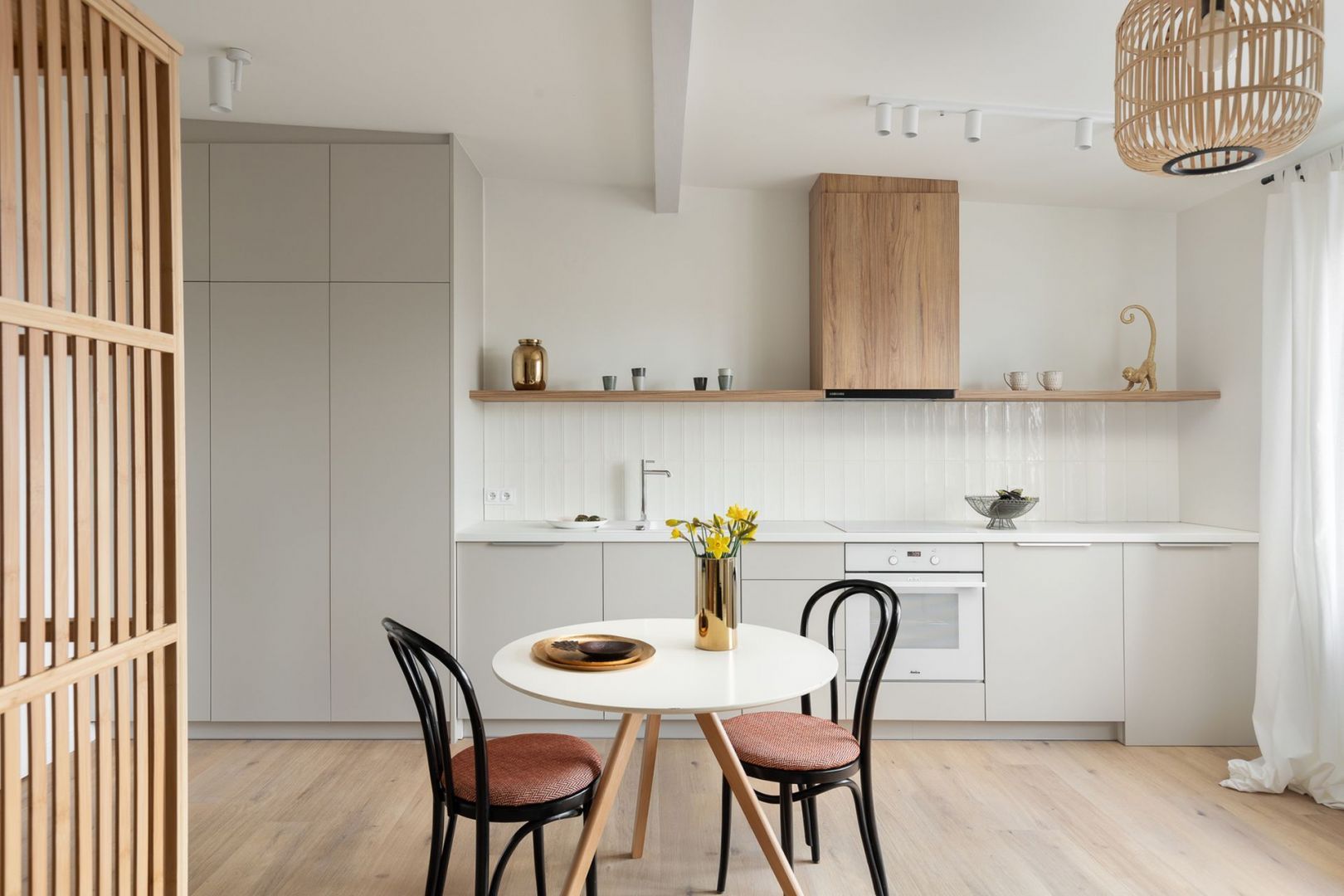 Ściana nad blatem w kuchni wykończona jest białymi płytkami. Idealnie pasują one do jasnych mebli oraz do drewnianych elementów. Projekt: Ola Dąbrówka, GOOD VIBES Interiors. Fot. Mikołaj Dąbrowski