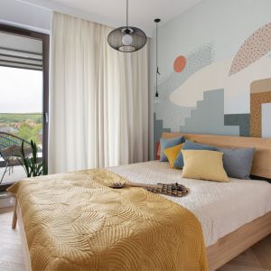 Ściana za łóżkiem w sypialni wykończona jest tapetą z kolorowym, geometrycznym wzorem. Projekt: Marta Kodrzycka, Marta Wróbel, Grupa Malaga. Fot. Magdalena Łojewska