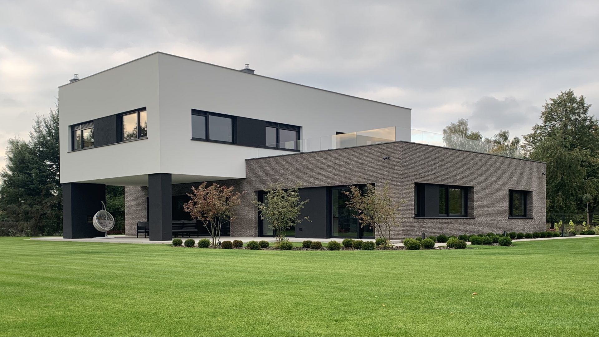 Elewacja budynku wykończona naturalną cegłą i białym tynkiem delikatnie wpisuje się w otoczenie. Projekt i zdjęcia: TRZY.BE Architekci