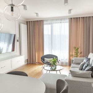 W jasnym, stylowym salonie świetnie prezentują się ciemniejsze zasłony i białe firanki. Są piękną ozdobą okna. Projekt: Studio Projektowania Miśkiewicz Design. Fot. Anna PowałowskaW
