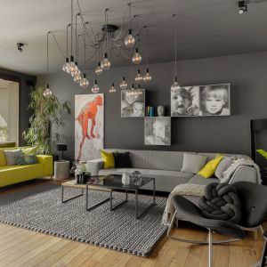 Ciemny, szary fotel w zestawie z szarą i żółtą kanapą. Projekt: Maja i Marek Kostykiewicz, alekosmos.com. Fot. Aleksandra Dermont
