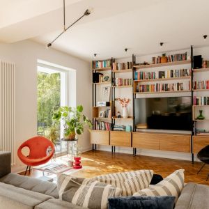 Fotel w pomarańczowym kolorze jest fajnym akcentem w stonowanym, jasnym salonie pełnym światła. Projekt: Antonina Sadurska i Katarzyna Burak, Fuga Architektura Wnętrz. Fot. Aleksandra Dermont