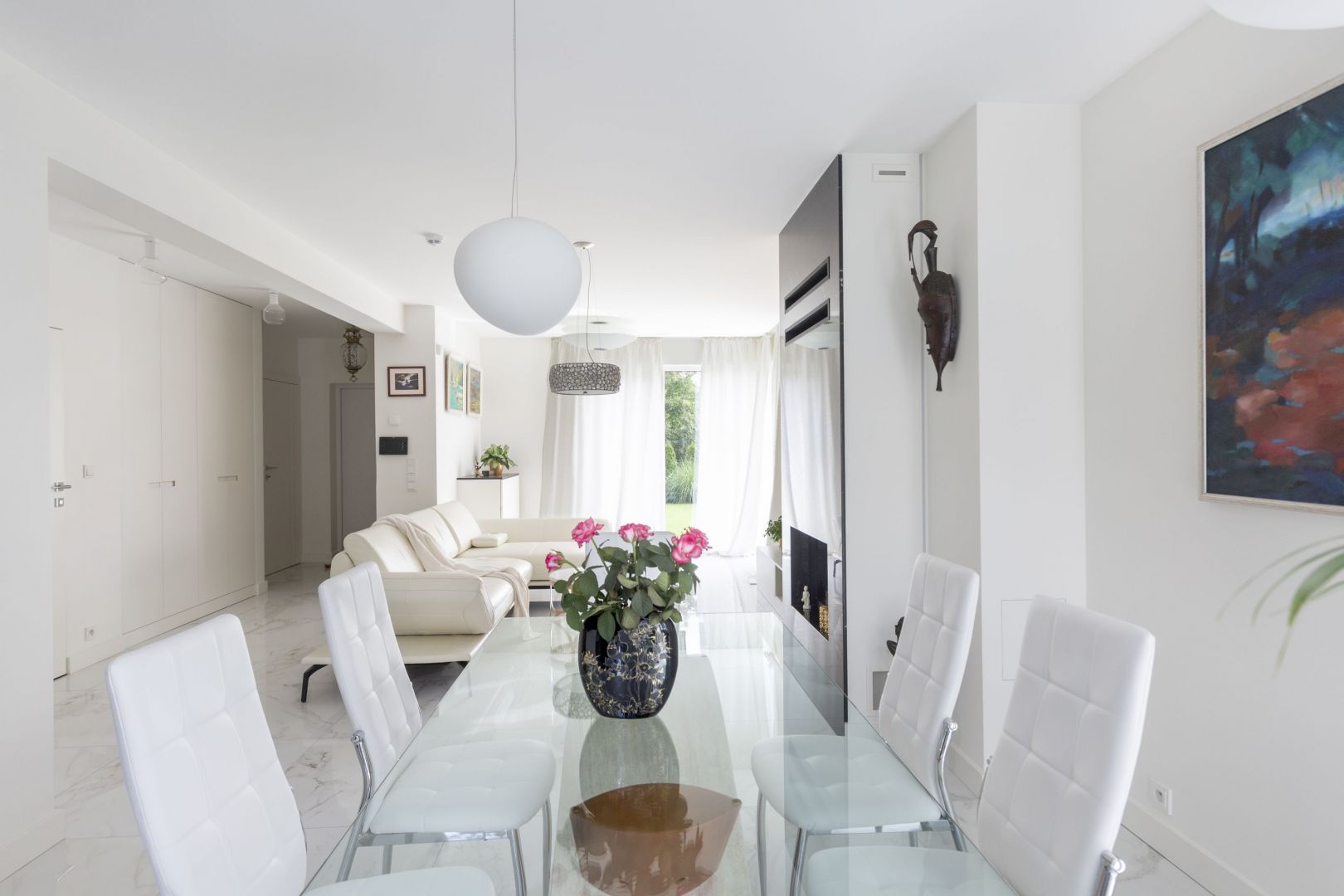 Przy salonie znajduje się wygodna jadalnia z dużym stołem w białym kolorze. Białe są też krzesła. Projekt: Katarzyna Rohde, Home&Style. Fot. PionPoziom