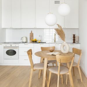 Biała kuchnia i drewniany stół z krzesłami. Projekt: pracownia Nasze Nowe. Zdjęcia: Marta Behling, Pion Poziom