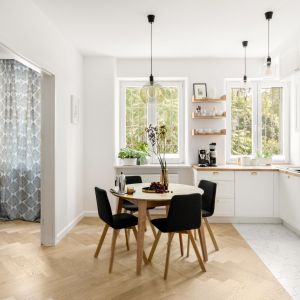 Okrągły drewniany stół i czarne, tapicerowane krzesła w salonie i kuchni w stylu boho. Projekt wnętrz Boho Studio. Zdjęcia: Aleksandra Dermont