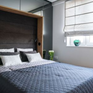 Ścianę za łóżkiem w małej sypialni wykorzystano bardzo praktycznie. Projekt: Dariusz Grabowski, Dagar Studio. Zdjęcie: Karolina Wargocka-Kusz