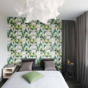 Ton aranżacji małej sypialni nadaje kolorowa tapeta na ścianie za łóżkiem. Projekt: Katarzyna Moraczewska. Fot. Bartosz Jarosz
