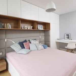 Zabudowa na ścianie za łóżkiem zapewnia sporo miejsca na przechowywanie w małej sypialni. Projekt: Przemek Kuśmierek. Zdjęcie: Bartosz Jarosz