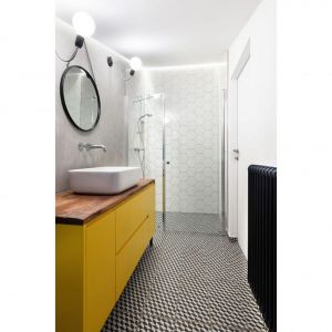 W łazience z prysznicem wykonany przez sztukatora beton świetnie łączy się z heksagonowymi, białymi płytkami. Projekt: biuro projektowe Miastoprojekty. Zdjęcie: Norbert Banaszyk