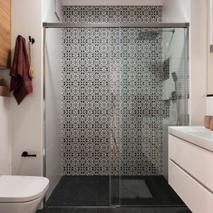 Łazienka z komfortowym prysznicem. Ściany zdobią geometryczne wzory płytek w kolorze czerni i bieli. Projekt i zdjęcie: KODO Projekty i Realizacje Wnętrz