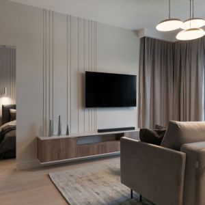 Ścianę za telewizorem w salonie zdobią pionowe listwy ścienne, optycznie zwiększające wysokość pomieszczenia. Projekt i zdjęcie: KODO Projekty i Realizacje Wnętrz
