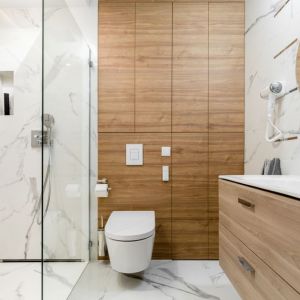 Nowoczesna łazienka z prysznicem bez brodzika, w której biel z rysunkiem marmuru pięknie łączy się z drewnem. Projekt i zdjęcia: Monika Staniec