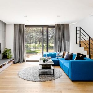 Niebieska sofa w jasnym salonie jest mocnym elementem wnętrza. Projekt: Paula Selerowicz Projektowanie Wnętrz. Fot. Aleksandra Dermont