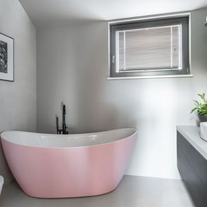 Ściany w łazience wykończona są szarą farbą na tle, której pięknie prezentuje się różowa wanna. Projekt: Daria Przewłócka. Fot. Natalia Kaczmarek, Inkadr