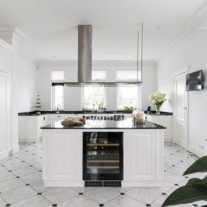 Okap w klasycznie urządzonej biało-czarnej kuchni z wyspą. Projekt wnętrza: Piotr Łucyan, Art’Up Interiors. Zdjęcia: Ład Studio