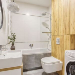 Drewniana zabudowa skrywa sporą ilość miejsca na przechowywanie w małej łazience w bloku. Projekt i zdjęcia: Deer Design Pracownia Architektury, deerdesign.pl