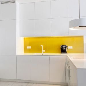 Ścianę nad blatem w kuchni zdobi szkłem w żółto-złotym kolorze. Projekt: Irmina Miernikiewicz. Fot. Katarzyna Dobosz