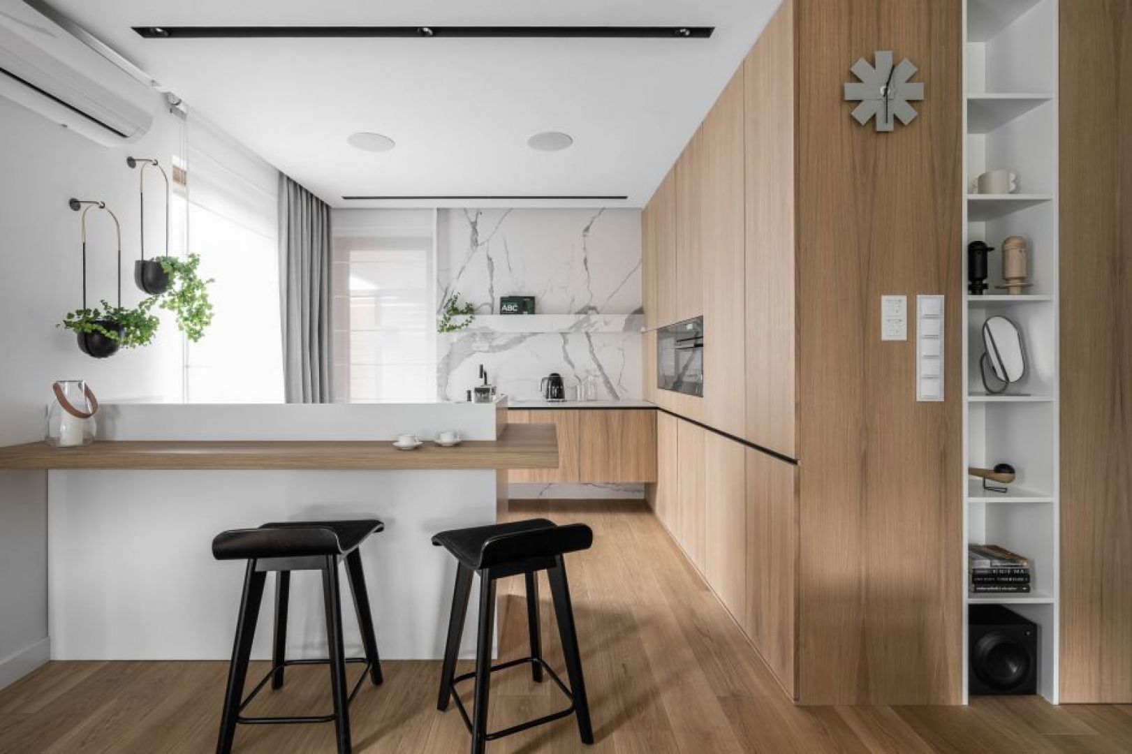 Kolor biały i jasne drewno tworzą eleganckie połączenie w kuchni otwartej na salon. Projekt: Anna Maria Sokołowska. Fot. Fotomohito