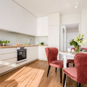 Białe meble kuchenne pięknie uzupełnia jasny, drewniany blat oraz podłoga. Projekt: Joanna Nawrocka, JN Studio. Fot. Łukasz Bera