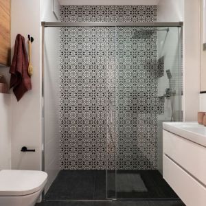 Wygodna łazienka z prysznicem. Geometryczne wzory płytek w kolorze czerni i bieli nadają jej charkteru. Projekt i zdjęcie: KODO Projekty i Realizacje Wnętrz