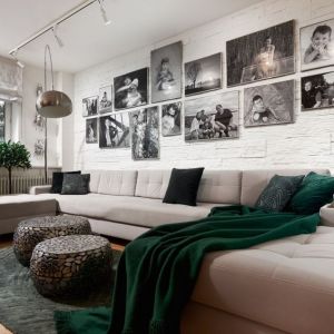 Ścianę za kanapą w salonie zdobi biały kamień, na którym pięknie wyeksponowana została rodzinna galeria zdjęć. Projekt: Dariusz Grabowski, Dagar Studio. Fot. Marek Królikowski