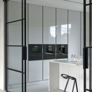 Kuchnię od salonu można oddzielić szklanym, osadzonym na czarnej, industrialnej ramie, systemem drzwi przesuwnych. Fot. Zajc

