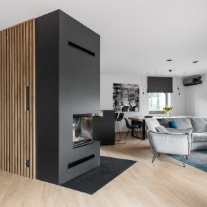 Kominek obudowany antracytową ceramiką o fakturze łupka wyznacza granicę pomiędzy strefą dzienną a częścią prywatną gospodarzy. Projekt: Studio Projekt, Dekorian Home. Fot. Fotomohito