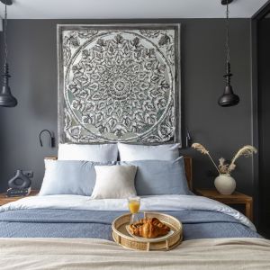 W sypialni znajduje się duże, wygodne łóżko z litego drewna mango i stoliki nocne z tego samego materiału oraz lustro w indyjskiej, rzeźbionej ramie. Projekt: Marta Dąbek, pracownia Interio. Zdjęcia: Pion Poziom