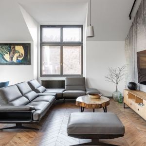 Szara sofa w skórzanej tapicerce w salonie urządzonym w stylu loftwym. Projekt: Daria Przewłócka. Fot. Natalia Kaczmarek, Inkadr
