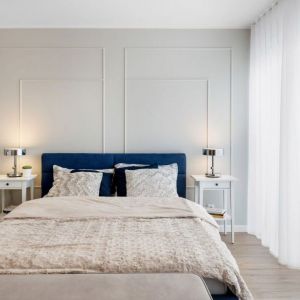 Jasna sypialnia z dużym, tapicerowanym łóżkiem w ciemnym niebieskim kolorze. Projekt: Joanna Nawrocka, JN Studio Joanna Nawrocka. Fot. Łukasz Bera
