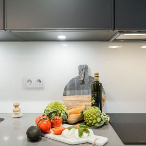Ścianę nad blatem w kuchni zabezpiecza bezbarwne szkło. Projekt i zdjęcia: KODO Projekty i Realizacje Wnętrz