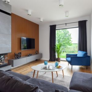 Ścianę za telewizorem wykonano z lameli drewnianych, które można zauważyć również w innych pomieszczeniach. Projekt wnętrza: Decoroom. Fot. Marek Koptyński