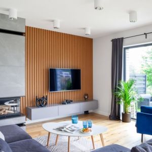 Drewniane lamele na ścianie w salonie. Projekt wnętrza: Decoroom. Fot. Marek Koptyński
