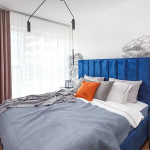 Sypialnia z niebieskim łóżkiem tapicerowanym i pastelowymi zasłonami. Projekt wnętrza Ewa Grzywa, architekt wnętrz Decoroom. Zdjęcia Marek Koptyński