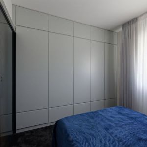 Czerń i drewno w małej sypialni w bloku. Projekt wnętrza: pracownia M-Studio. Fot. Radek Słowik