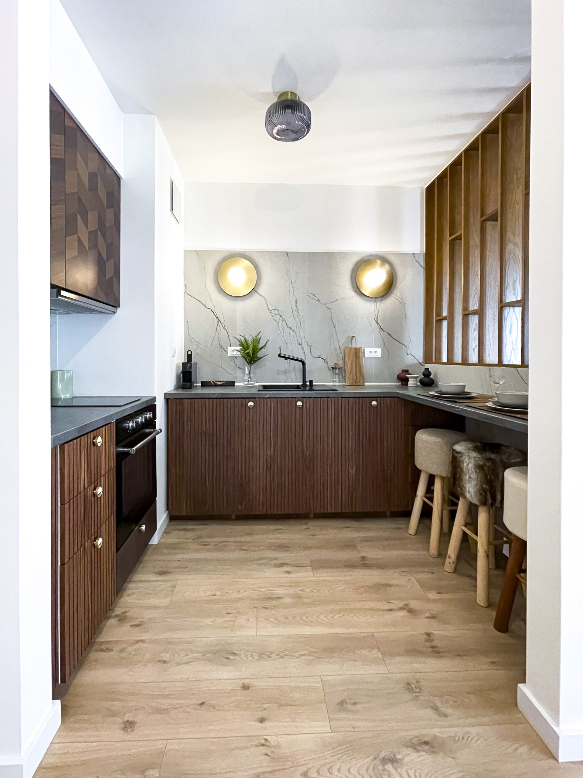 Mała i wąska kuchnia. Brązowe fronty to IKEA, personalizowana w pracowni Fropt. Jasno brązowa drewniana podłoga. Projekt wnętrza: Pogotowie Wnętrzarskie.  Fot. joannamajewska.photo