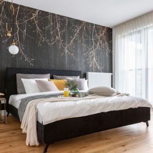 Tapeta ze złotymi gałązkami na ścianie za łóżkiem w sypialni. Projekt wnętrza: Decoroom. Fot. Marta Behling, Pion Poziom