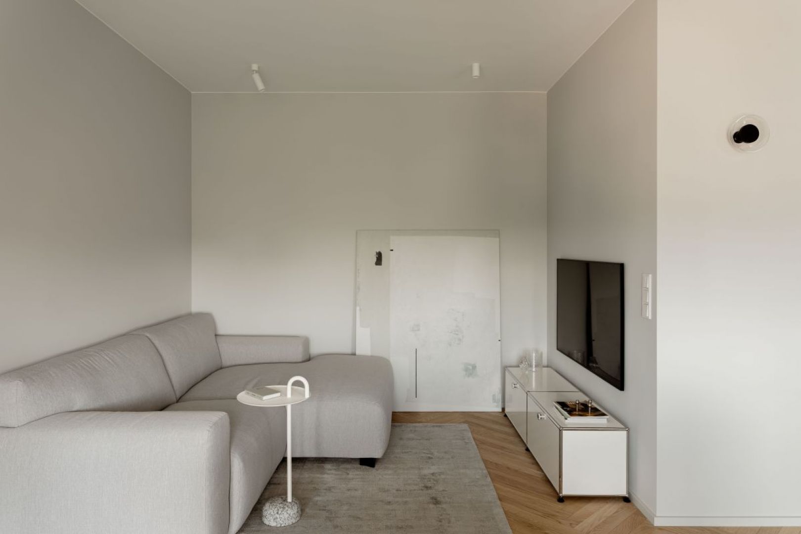 W strefie wypoczynkowej znajduje się jasnoszara sofa marki MTI Furninova z białym stolikiem marki Hay. Projekt wnętrza: 3XEL Architekci. Fot. PORA studio