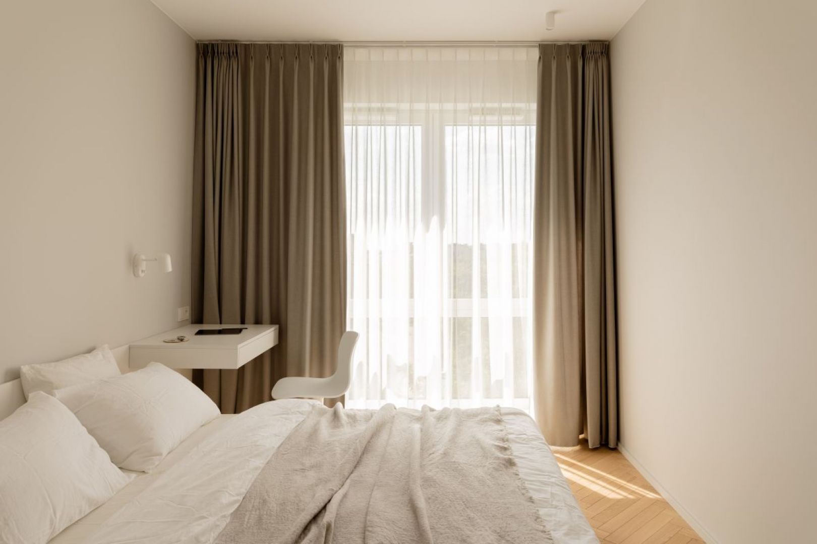 Jasną, wygodną sypialnię utrzymano w odcieniach bieli i beży. Projekt wnętrza: 3XEL Architekci. Fot. PORA studio