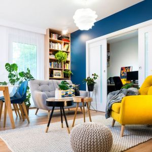 Szara sofa i żółty fotel w małym salonie w bloku. Projekt wnętrza: Krystyna Dziewanowska, Red Cube Design. Fot. Mateusz Torbus 7TH Idea
