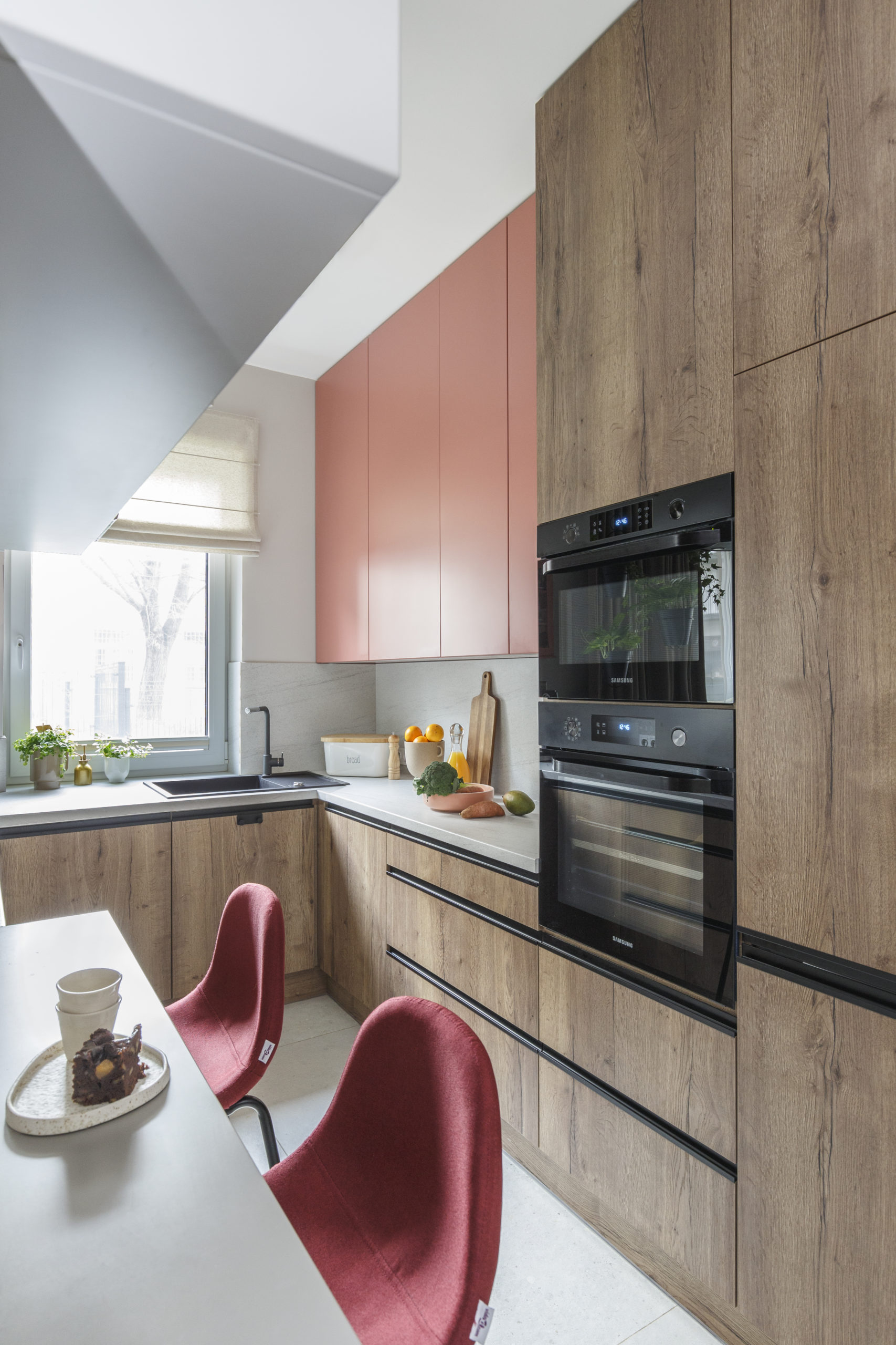 W kuchni widzimy szafki w kolorze drewna połączone z różowymi frontami. Projekt: Magdalena Dyoniziak-Sędzicka, pracownia Nasze Nowe. Fot. Marta Behling/Pion Pioziom