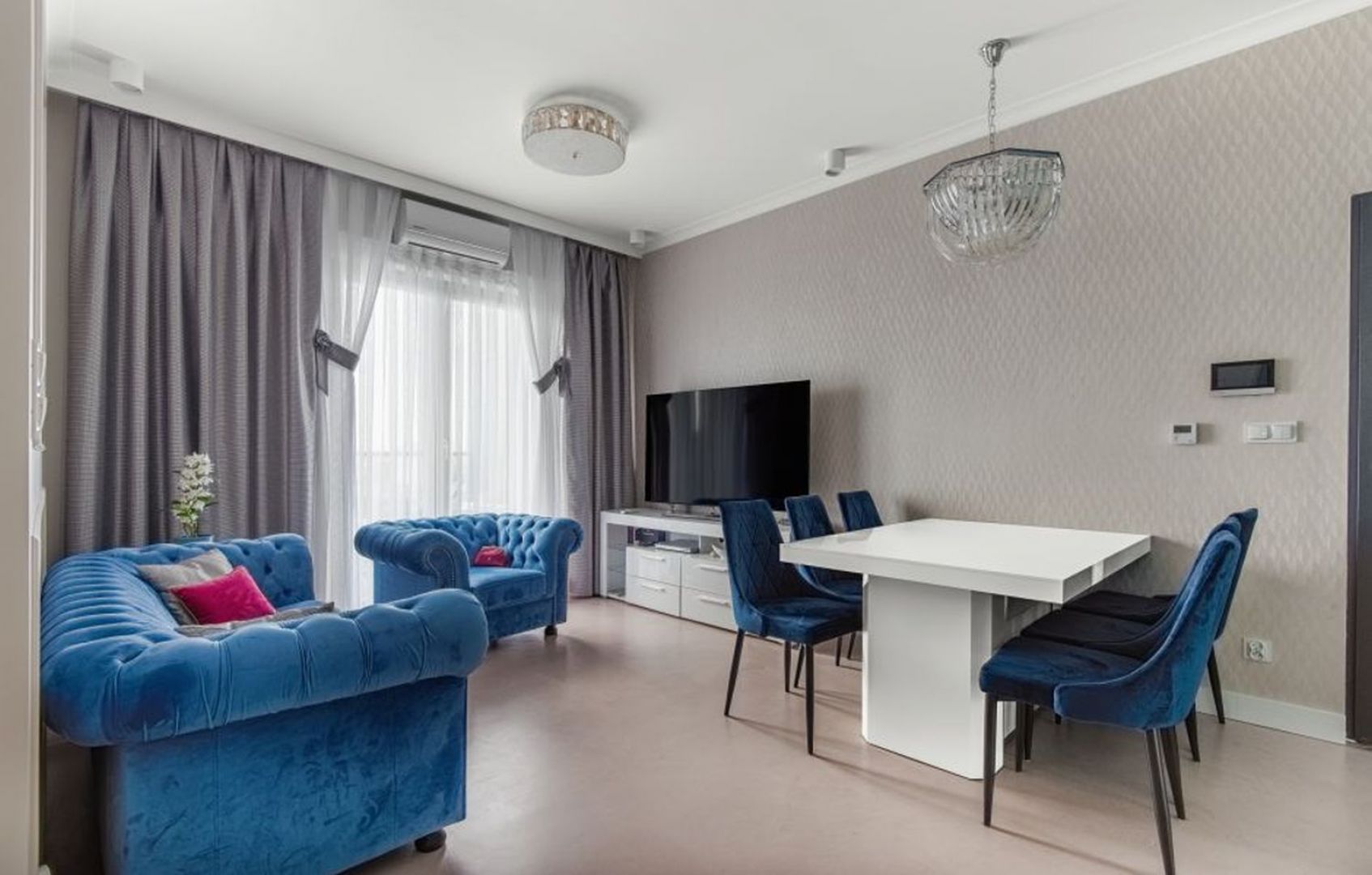 Elegancki salon z niebieską kanapą i jasnymi sztukateriami. Projekt wnętrza: Beata Ignasiak, pracownia Ignasiak Interiors. Zdjęcia: Grupa Deix